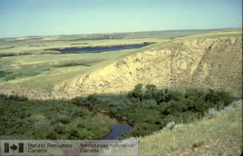 Photo 1999-043D : Berge haute exposant du till surmonté de dépôts glaciolacustres, avec dépôts postglaciaires emboîtés dorigine fluviatile et provenant de lérosion des  ...