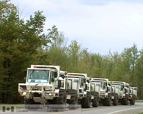 Photo 2002-579 : Convoi de camions vibrosismiques le long de la route de Smiths Falls, en Ontario. Les camions produisent simultanément une onde sonore à fréquence  ...