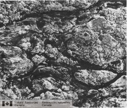 Photo 2002-786 : Pli F1 en fourreau dans une brèche de coulée rhyolitique bréchifiée tectoniquement comportant une matrice calco-mylonitique, à lest du lac Jim  ...