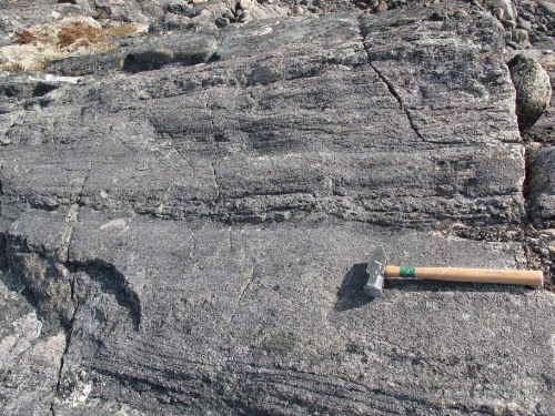 Photo 2015-124 : Quartz and feldspar rodding in layered orthopyroxene-biotite monzogranite in the hinge zone of open D2 M folds - fold axis is parallel to the hammer  ...