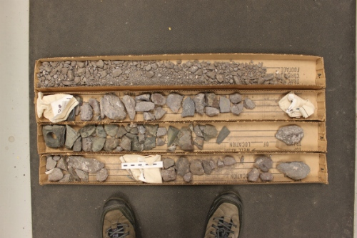 Photo 2019-302: Core box sleeves with red-brown to olive green coloured basalt showing the rubbly and weathered nature of the core (scale bar is 10 cm in length).