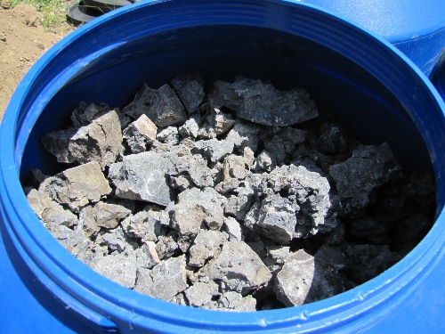 Photo 2020-619: Top view of the leach test barrels. The slag consists of weathered gravel (1 cm) to cobble-sized (12 cm) material with a vesicular texture. The card  ...