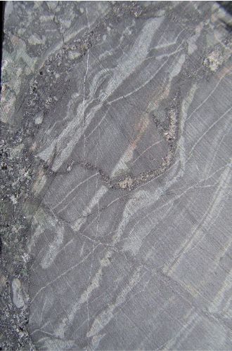 Photo 2020-725: High-temperature Ca-Fe alteration with stratabound amphibole, magnetite and albite alteration of a sedimentary host cut by a magnetite vein  in drill  ...