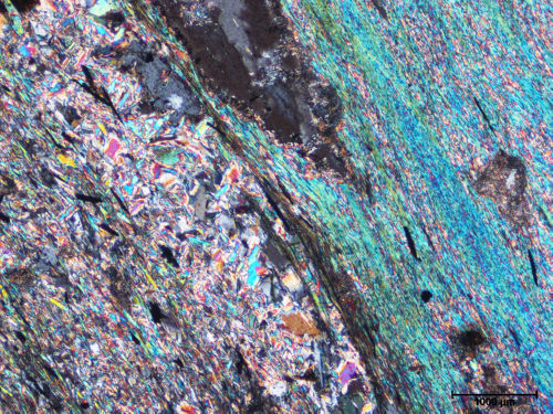 Photo 2021-694: Photomicrograph (cross-polarized transmitted light) of the intense proximal alteration assemblage, showing the two types of sericites observed within  ...