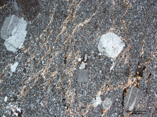 Photo 2021-702: Photomicrograph (cross-polarized transmitted light) of fracture-controlled sericite observed within the volcaniclastic felsic unit (5.3a-(b)) hosting  ...