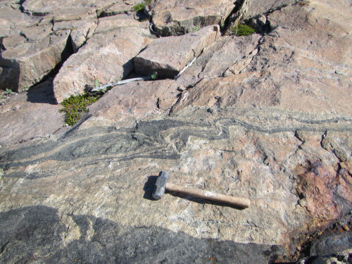 Photo 2022-273: 12413/18CXAD0069B01- foliated monzogranite, Webb Bay.  Hammer approx. 60 cm long
