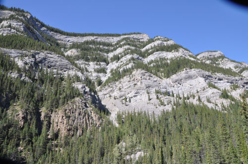 Photo 2022-386: Fig. 11. The Banff Formation and the overlying limestones of the Rundle Group seen from the mouth of the side canyon of Jura Creek (measured by B.C.  ...