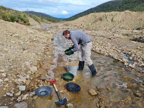 Photo 2022-451 : An example of GSC geologist, Chris Beckett-Brown discarding the 2-10 mm clast fraction at sample site 115J221004 following wet sieving the bulk  ...