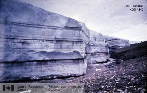 Photo KGS-1445 : Bordure est du glacier Henrietta Nesmith; remarquer l'eau qui s'écoule du dessus du glacier et le torrent fluvio-glaciaire en bordure. Le géologue  ...