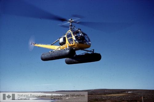 Photo KGS-255 : Hélicoptère en vol sur place avant d'atterrir à la station radio du lac Ennadai. Le lac gelé à l'avant-plan gauche inférieur.
