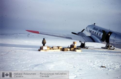 Photo KGS-5 : Un géologue, son assistant, un Inuit et un attelage de chiens qui descendent d'un DC-3 à Port Leopold, île Somerset. L'équipe a effectué la  ...