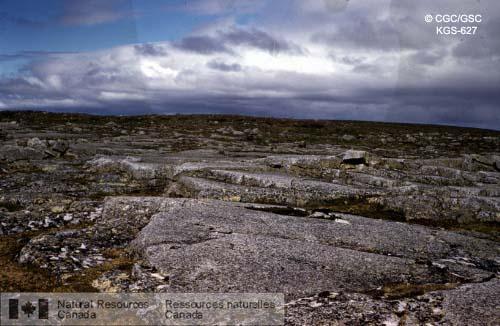 Photo KGS-627 : Opération Thelon. Terres  rocheuses stériles recouvrant des roches granitiques dans une région au relief peu accidenté, au nord-est du lac  ...